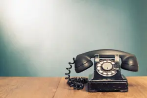 Altes Telefon mit Drehscheibe in schwarz auf einem Tisch