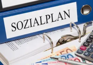 Ordner mit Aufschrift Sozialplan, Taschenrechner und Geld